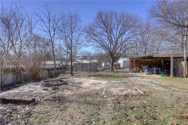 view of yard featuring a fire pit, a pole building, an outdoor structure, and fence