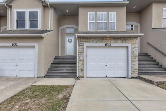 view of property featuring stone siding, stucco siding, driveway, and a garage