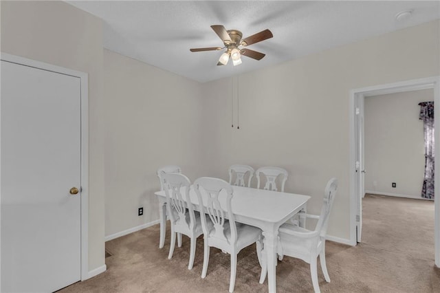 dining area with ceiling fan, baseboards, and light carpet