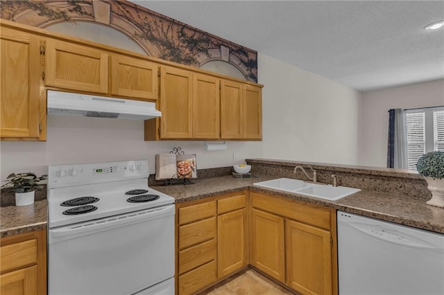 kitchen featuring under cabinet range hood, dark stone countertops, a sink, a textured ceiling, and white appliances