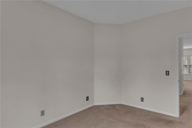 unfurnished room with light colored carpet and baseboards