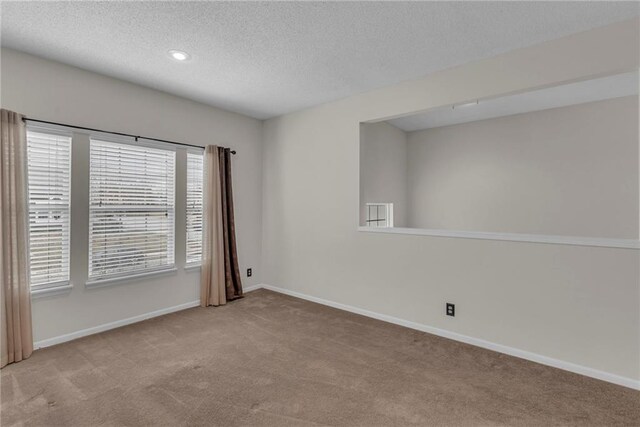 carpeted empty room with baseboards and a textured ceiling