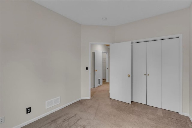 unfurnished bedroom featuring visible vents, light carpet, and baseboards