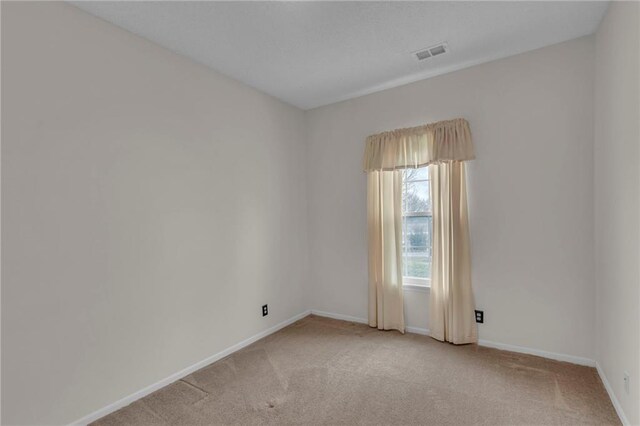 spare room featuring baseboards, visible vents, and light carpet