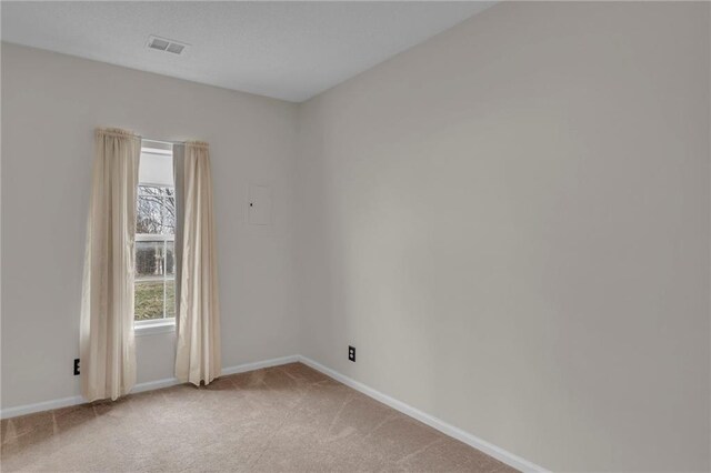 empty room featuring baseboards, light carpet, and visible vents