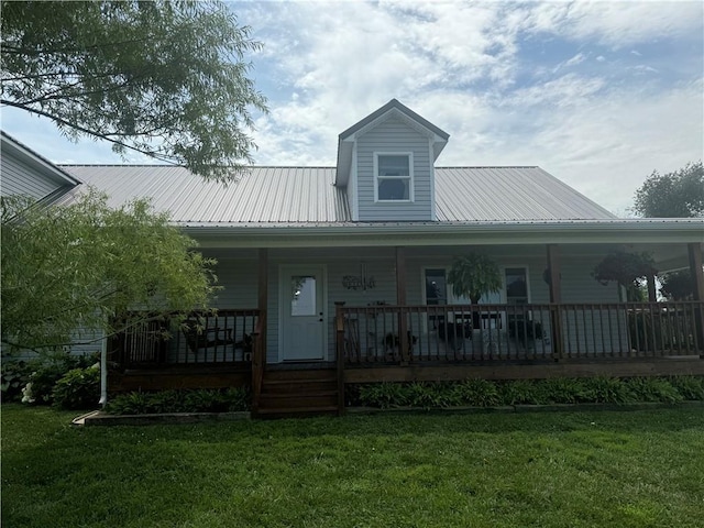 view of front of property featuring metal roof, covered porch, and a front lawn