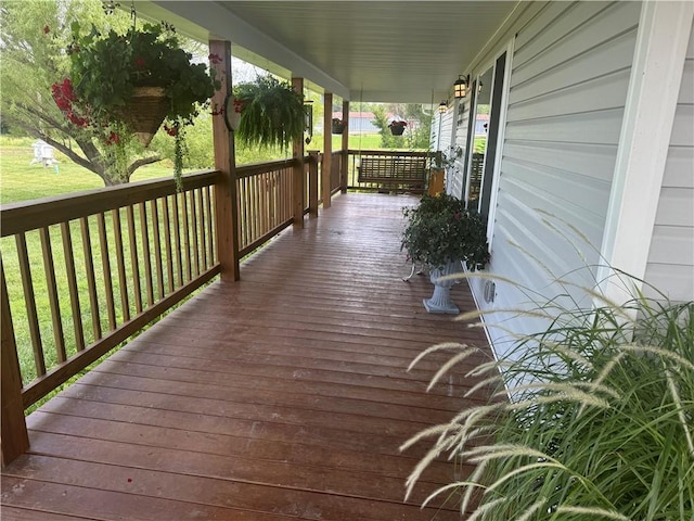 wooden terrace with a lawn and covered porch