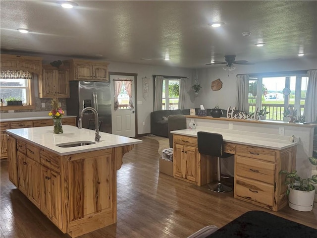 kitchen featuring dark wood-style floors, an island with sink, stainless steel fridge with ice dispenser, and a sink