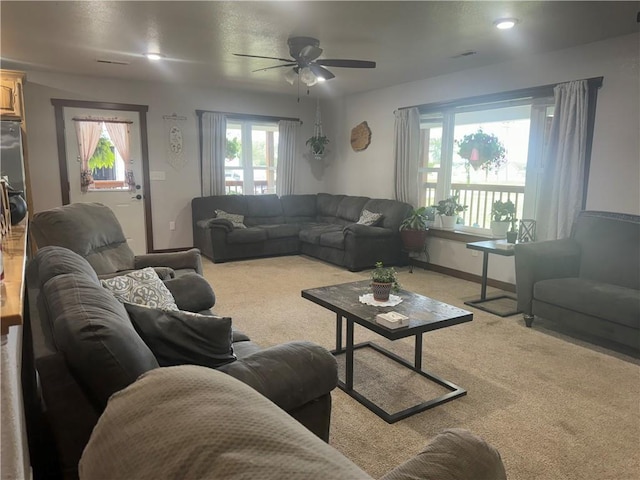 living area with visible vents, light carpet, baseboards, and ceiling fan