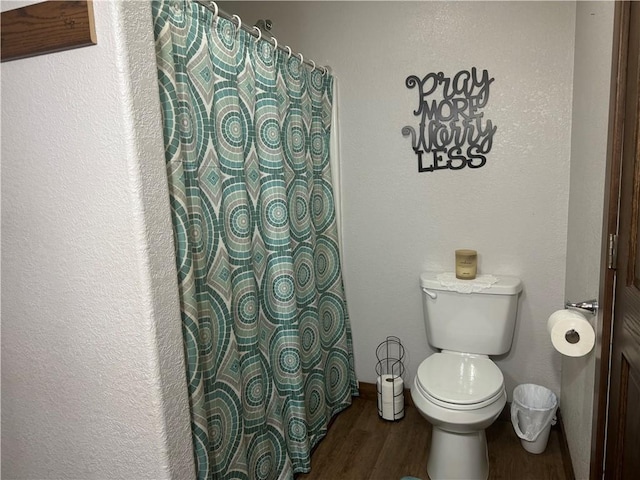 bathroom featuring a shower with shower curtain, toilet, and wood finished floors