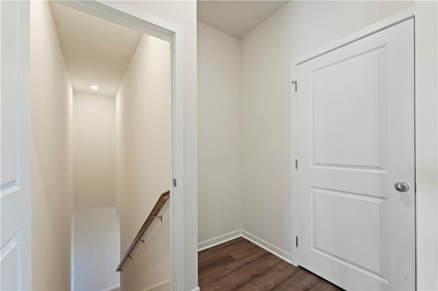 corridor with dark wood-style flooring, an upstairs landing, and baseboards