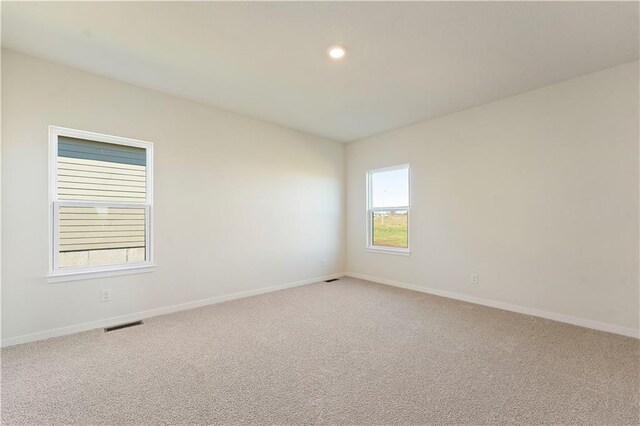 unfurnished room with light carpet, visible vents, baseboards, and recessed lighting