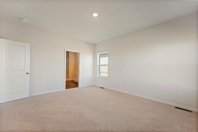 unfurnished bedroom with carpet floors, visible vents, ensuite bath, and baseboards