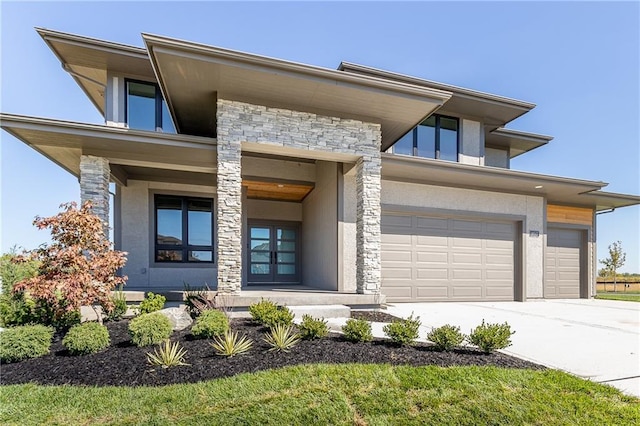 view of front of property featuring stone siding, an attached garage, driveway, and stucco siding