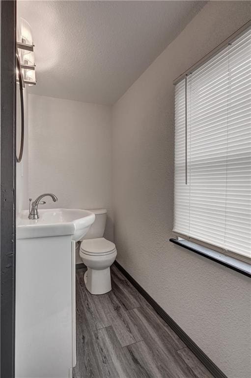 511 N E Ave, Columbus, KS 66725 - half bath featuring vanity, wood finished floors, toilet, a textured ceiling, and baseboards
