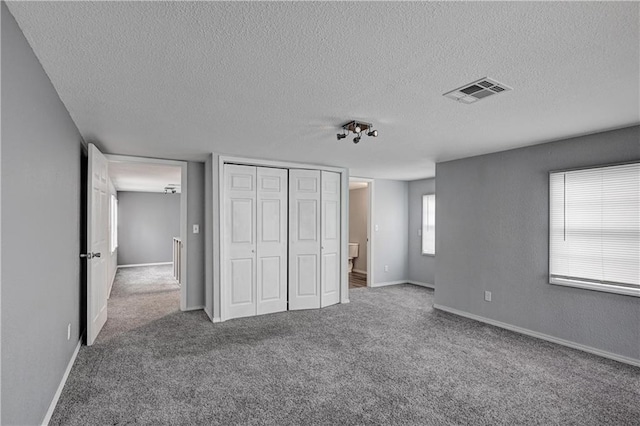 511 N E Ave, Columbus, KS 66725 - unfurnished bedroom with carpet flooring, a textured ceiling, a closet, and baseboards
