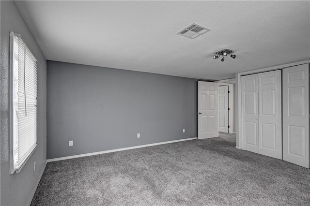 511 N E Ave, Columbus, KS 66725 - unfurnished bedroom with carpet flooring, baseboards, multiple windows, and a textured ceiling
