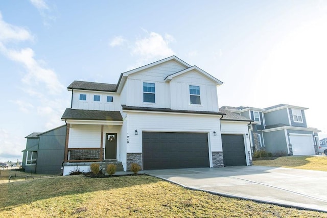 view of front of house with an attached garage, board and batten siding, fence, driveway, and a front lawn