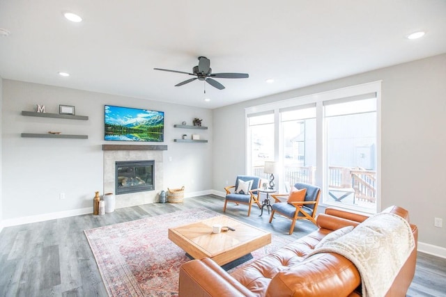 living room featuring recessed lighting, a fireplace, baseboards, and wood finished floors