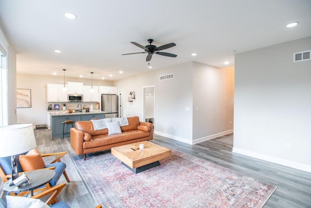 living room featuring light wood-style floors, recessed lighting, visible vents, and baseboards