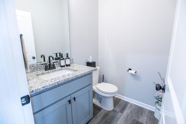 bathroom featuring toilet, baseboards, wood finished floors, and vanity