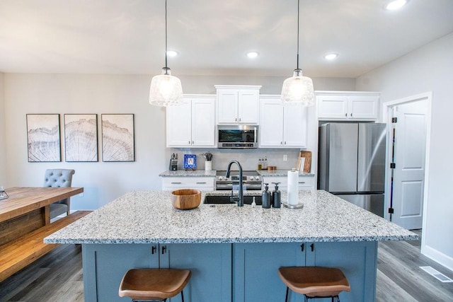 kitchen featuring stainless steel appliances, white cabinets, visible vents, and a kitchen bar