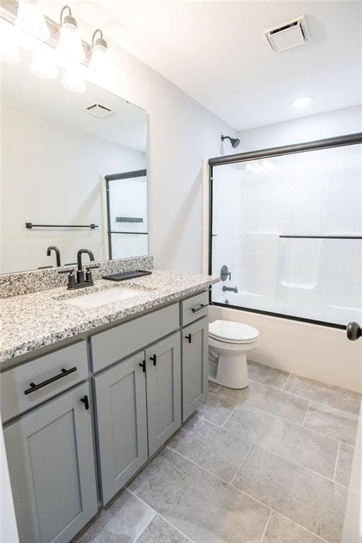 bathroom featuring toilet, shower / bath combination with glass door, visible vents, and vanity