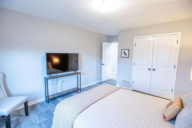 bedroom featuring baseboards, a closet, visible vents, and wood finished floors