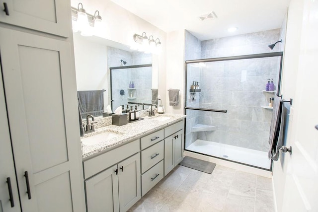 bathroom featuring double vanity, a stall shower, a sink, and visible vents