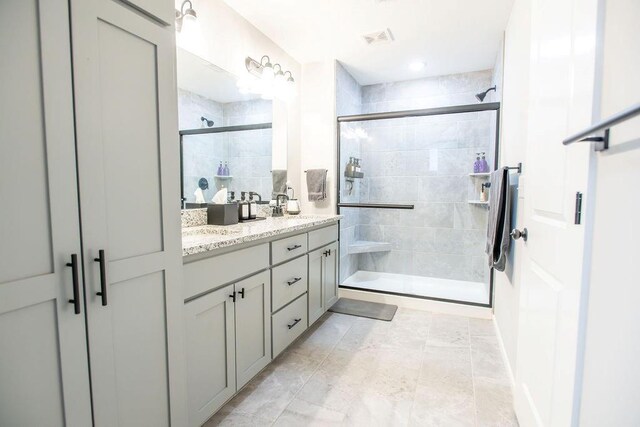 full bath featuring a sink, double vanity, a shower stall, and visible vents