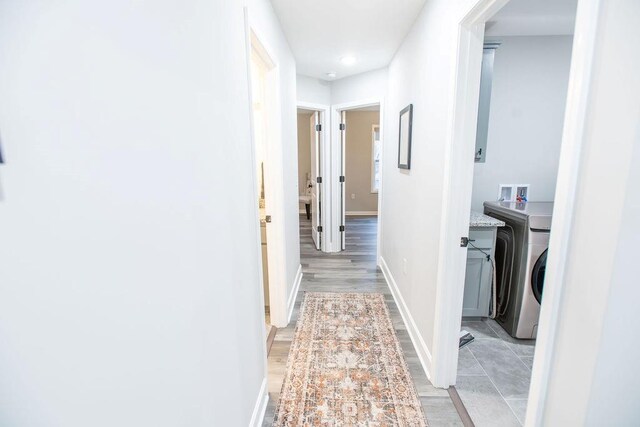 hall featuring washer / dryer, light wood-style floors, and baseboards