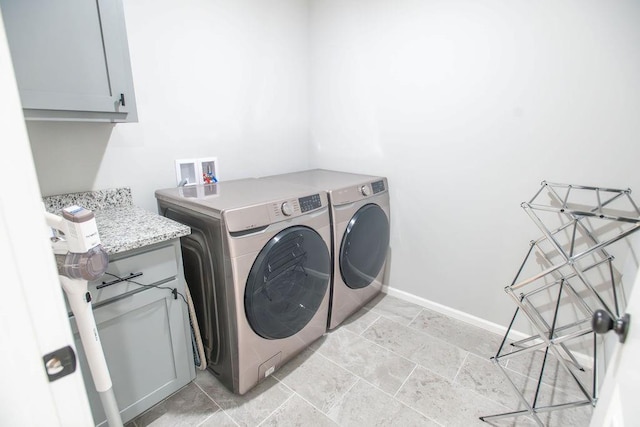 laundry room featuring washer and clothes dryer, cabinet space, and baseboards