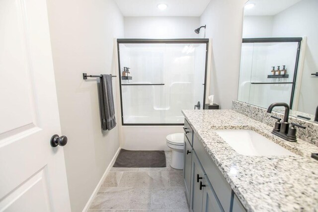 bathroom featuring bath / shower combo with glass door, vanity, toilet, and baseboards