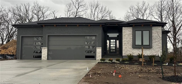 prairie-style house featuring a garage, stone siding, driveway, and stucco siding