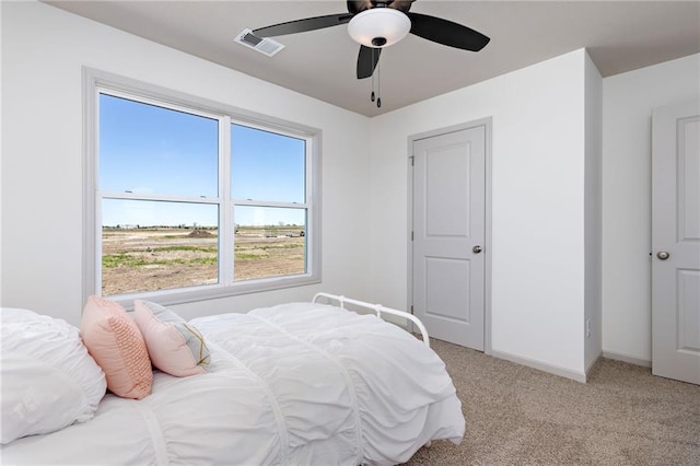 bedroom with light carpet, ceiling fan, visible vents, and baseboards