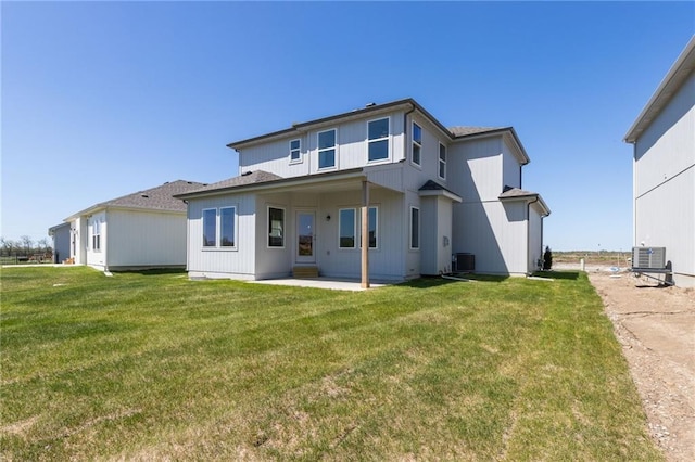 rear view of property with cooling unit, a patio area, and a lawn