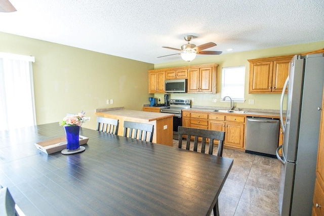 kitchen featuring a textured ceiling, stainless steel appliances, light countertops, and a sink