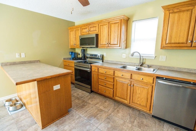 kitchen with a peninsula, stainless steel appliances, light countertops, and a sink