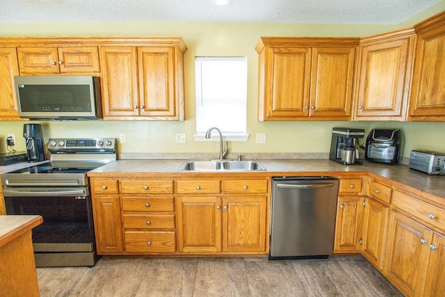 kitchen featuring a sink, brown cabinets, appliances with stainless steel finishes, and light wood finished floors