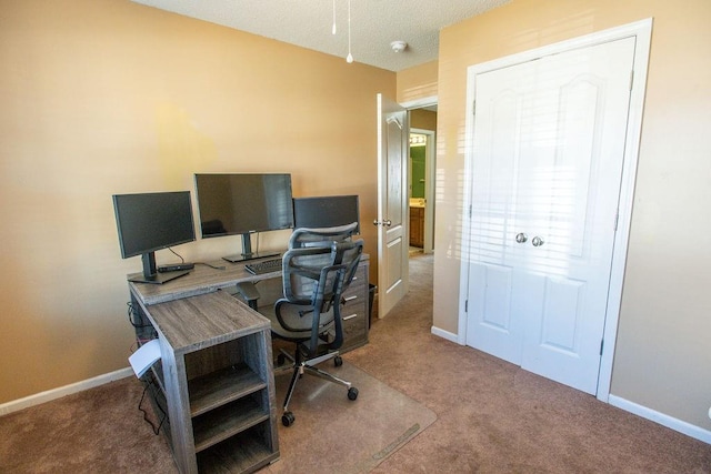 carpeted home office featuring baseboards and a textured ceiling