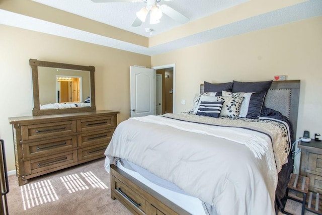 bedroom featuring light carpet, a ceiling fan, and a tray ceiling