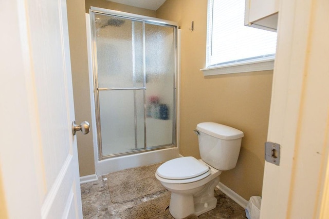 bathroom featuring a shower stall, toilet, and baseboards