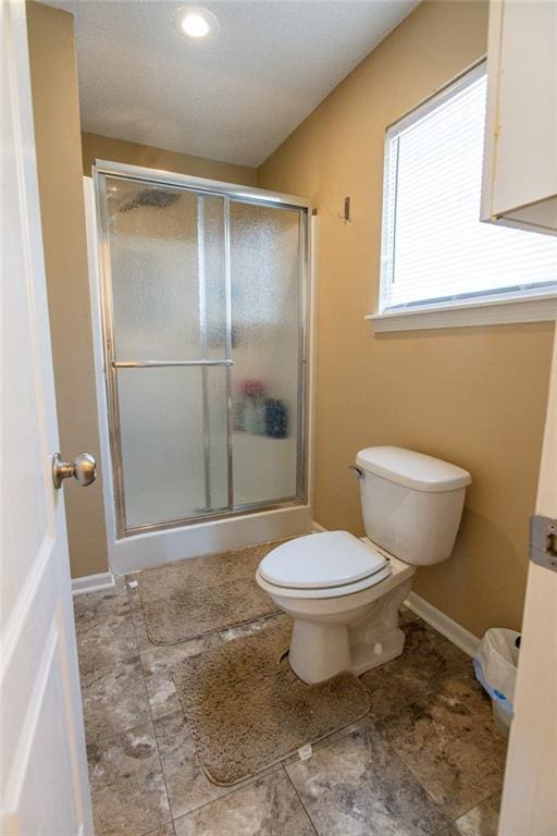 bathroom with toilet, baseboards, and a stall shower