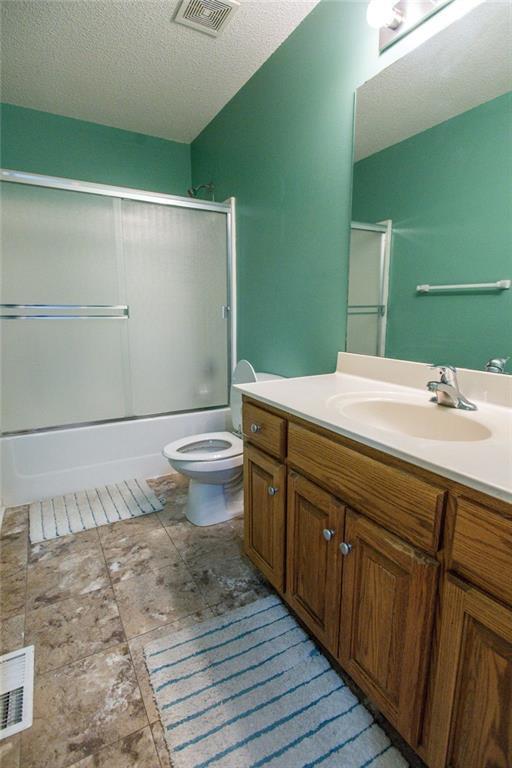 full bath featuring visible vents, toilet, vanity, and a textured ceiling