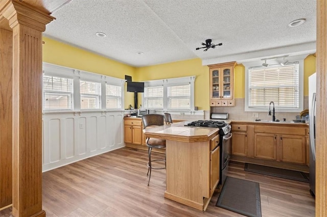 3820 Virginia Ave, Kansas City, MO 64109 - kitchen featuring glass insert cabinets, a kitchen bar, a textured ceiling, and gas range
