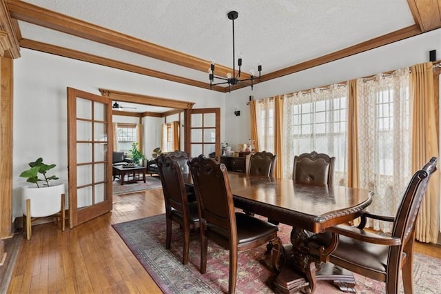 3820 Virginia Ave, Kansas City, MO 64109 - dining space featuring french doors, a textured ceiling, crown molding, wood-type flooring, and a chandelier