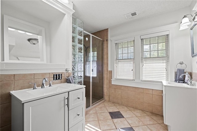 3820 Virginia Ave, Kansas City, MO 64109 - bathroom with tile walls, healthy amount of natural light, a stall shower, two vanities, and tile patterned flooring