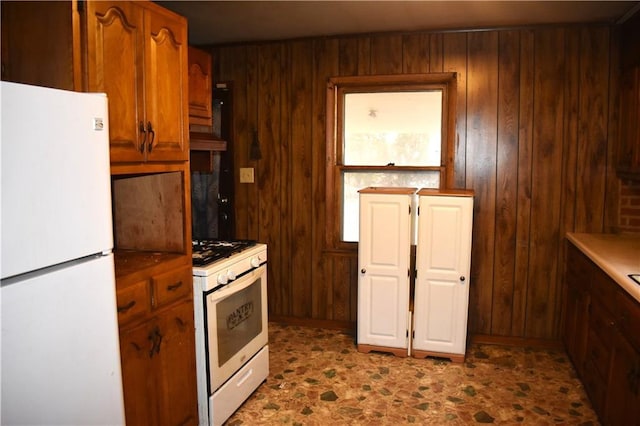 kitchen featuring white appliances, brown cabinets, and wood walls