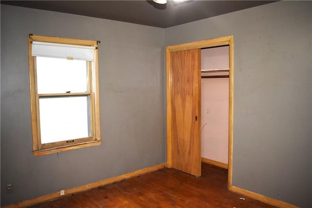 unfurnished bedroom with a closet, wood finished floors, and baseboards