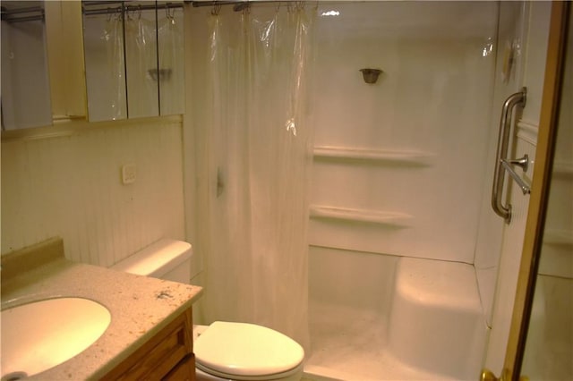 bathroom featuring toilet, a stall shower, and vanity